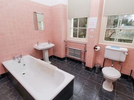 A bathroom with a bathtub a sink a toilet two windows and a radiator at Cheviot Manor in Akeld near Wooler