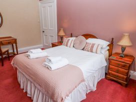A bedroom with a double bed with white and patterned pillows bedside tables with lamps and a wooden desk with a chair at Cheviot Manor in Akeld near Wooler