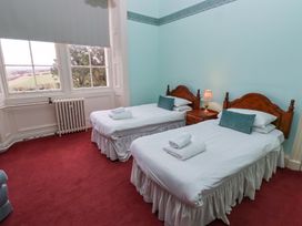 A bedroom with two single beds a bedside table with a lamp and a window showing trees at Cheviot Manor in Akeld near Wooler