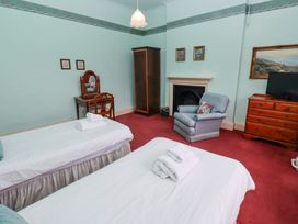 A bedroom with two single beds towels on beds a dressing table a chair a wardrobe an armchair a fireplace a TV on a wooden dresser and framed pictures on the wall at Cheviot Manor in Akeld near Wooler