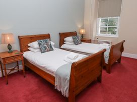 A bedroom with two wooden single beds white bedding decorative pillows bedside tables and lamps at Cheviot Manor in Akeld near Wooler