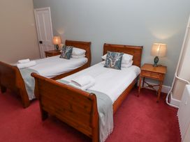 A bedroom with two single wooden beds bedside tables with lamps and folded towels at Cheviot Manor in Akeld near Wooler