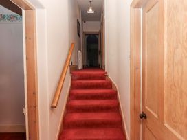 A narrow hallway with red carpeted stairs wooden doors and handrail at Cheviot Manor in Akeld near Wooler
