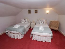 A bedroom with two single beds with folded towels and floral pillows a nightstand and a chair at Cheviot Manor Akeld near Wooler