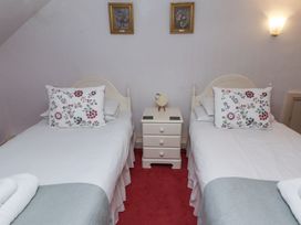 A bedroom with two single beds separated by a three drawer nightstand and floral pillows at Cheviot Manor in Akeld near Wooler