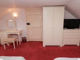 A room with a dressing table and stool, a wooden door, a wardrobe, a chest of drawers with a television on top at Cheviot Manor in Akeld near Wooler