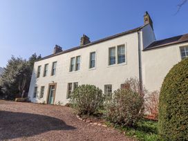 The exterior of a two story white house with several windows a door and bushes along a gravel driveway at Cheviot Manor Akeld near Wooler