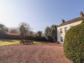A gravel area with two picnic tables beside a white house and a large round bush at Cheviot Manor Akeld near Wooler