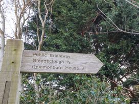 A wooden public bridleway signpost with directions and distances in a wooded area at Cheviot Manor in Akeld near Wooler