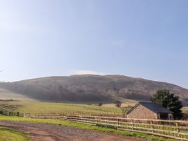A rural landscape with grassy fields a dirt path a stone building and hills in the background at Cheviot Manor in Akeld near Wooler
