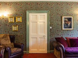 A living room with a door and framed paintings at Cheviot Manor Akeld near Wooler