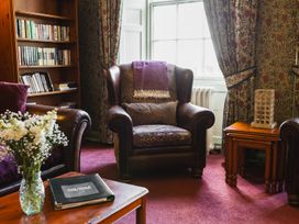 A living room with an armchair and bookshelf at Cheviot Manor in Akeld near Wooler
