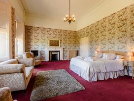 A bedroom with a bed and armchairs at Cheviot Manor in Akeld near Wooler