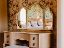 A dressing table with a mirror reflecting a bed at Cheviot Manor in Akeld near Wooler