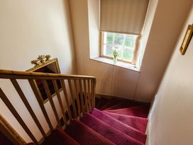 A staircase with a window and a mirror at Cheviot Manor in Akeld near Wooler