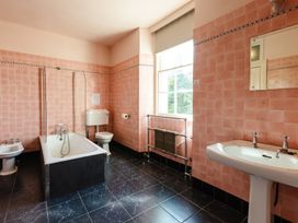 A bathroom with a bathtub, toilet, sink and window at Cheviot Manor Akeld near Wooler