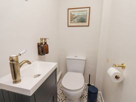 A small bathroom with a toilet sink soap dispensers toilet brush and trash bin at Sunny Side in Runswick Bay