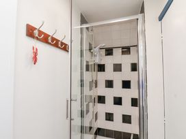 A shower area with black and white tiled walls and a hook rack on the wall at Sunny Side in Runswick Bay