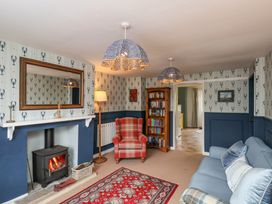 A living room with a wood burning stove armchair sofa bookshelf and patterned rug at Sunny Side in Runswick Bay
