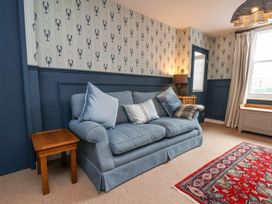 A sitting room with a blue couch pillows a wooden side table and a red patterned rug at Sunny Side in Runswick Bay