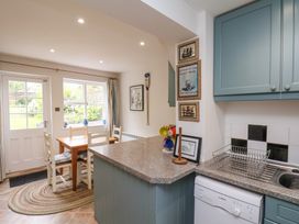 A kitchen and dining area with a wooden table and chairs near a window and door at Sunny Side in Runswick Bay