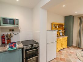 A kitchen with a stove microwave and utensils next to a yellow cabinet and white refrigerator at Sunny Side in Runswick Bay