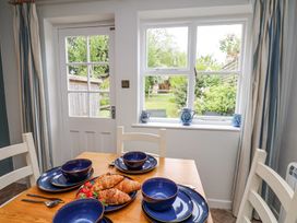 A dining table set with blue bowls and plates with croissants and strawberries near a door and window with a view of a garden at Sunny Side in Runswick Bay