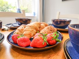 A plate with croissants and strawberries on a wooden dining table with blue cups and bowls in a kitchen at Sunny Side in Runswick Bay