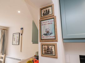 Three framed maritime-themed pictures on a wall next to blue kitchen cabinets at Sunny Side in Runswick Bay