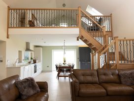 A living room with a staircase and kitchen view at Golygfa Cwrt Near Bontgoch and Penrhyncoch