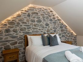 A bedroom with a stone wall and wooden furniture at Golygfa Cwrt near Bontgoch and Penrhyncoch