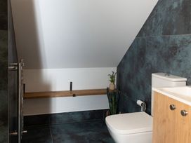 A bathroom with a toilet, sink, and wood shelf at Golygfa Cwrt Near Bontgoch and Penrhyncoch