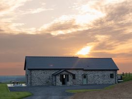 A stone house with a driveway and outdoor bench at Golygfa Cwrt near Bontgoch and Penrhyncoch
