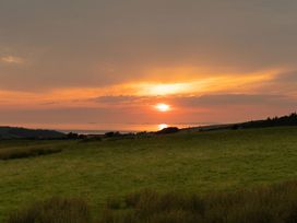 A sunset over a field and water at Golygfa Cwrt near Bontgoch and Penrhyncoch