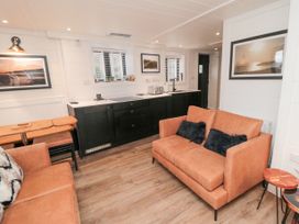 A kitchen and living area with two brown sofas black cabinets and framed pictures on the walls at The Blacksmith's Shop in Staithes