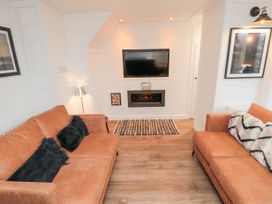 A living room with two brown sofas facing a wall mounted TV and fireplace at The Blacksmith's Shop in Staithes