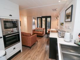 A kitchen and living area with ovens, brown sofas, countertop appliances, and glass doors at The Blacksmith's Shop in Staithes