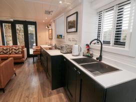 A kitchen with black cabinets and white countertops next to a living area with brown sofas at The Blacksmith's Shop in Staithes