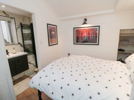 A bedroom with a bed featuring star-patterned bedding a bathroom with a sink and towel rack and framed pictures on the walls at The Blacksmith's Shop in Staithes