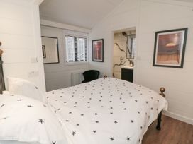 A bedroom with a bed covered in star patterned bedding a black chair two framed pictures and a bathroom at The Blacksmith's Shop in Staithes