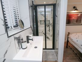 A bathroom with a sink soap dispenser and shower next to a bedroom with a bed at The Blacksmith's Shop in Staithes