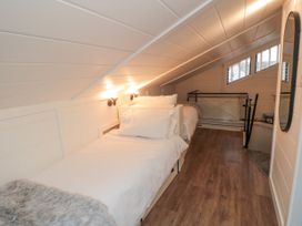 A bedroom with two single beds under a sloped ceiling and wooden floor at The Blacksmith's Shop in Staithes