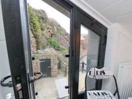 A door opening to an outdoor area with a stone wall and a small door a black chair with Paris text and a radiator inside the room at The Blacksmith's Shop in Staithes