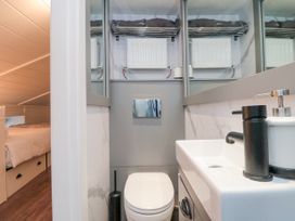 A small bathroom with a toilet sink and mirror adjacent to a bedroom at The Blacksmith's Shop in Staithes