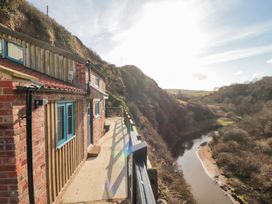A house with a balcony overlooking a river and hills at The Blacksmith's Shop in Staithes