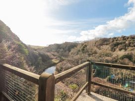 A wooden balcony with wire mesh overlooking a river and wooded hills at The Blacksmith's Shop in Staithes