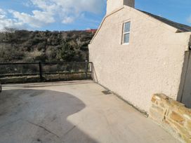 An outdoor paved area next to a beige building with a window and a stone wall at The Blacksmith's Shop in Staithes