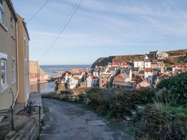 A narrow road leading down to a coastal village with houses and the sea in the background at The Blacksmith's Shop in Staithes