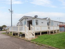 A mobile home with a fenced wooden deck and steps in a residential area at Hazel Park Lodge HP4 in Rhyl