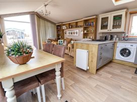 An open living room and kitchen area with a dining table with a flower basket on it at Hazel Park Lodge HP4 Rhyl